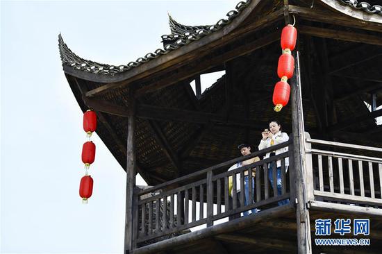  游客在重慶市武隆區(qū)黃鶯鄉(xiāng)復(fù)興村的觀景樓上欣賞田園景色（2019年3月28日攝）。 新華社記者 劉潺 攝